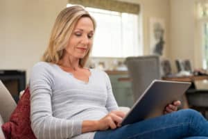 Mature woman sitting down and looking at an iPad