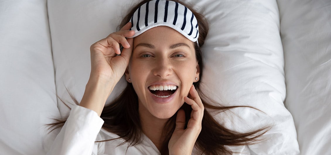 smiling woman lifting sleeping mask