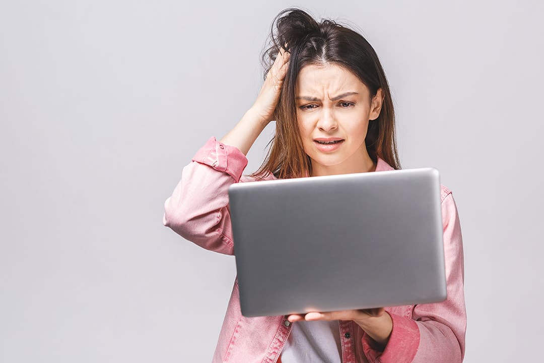 Young woman looking sceptically at her laptop computer