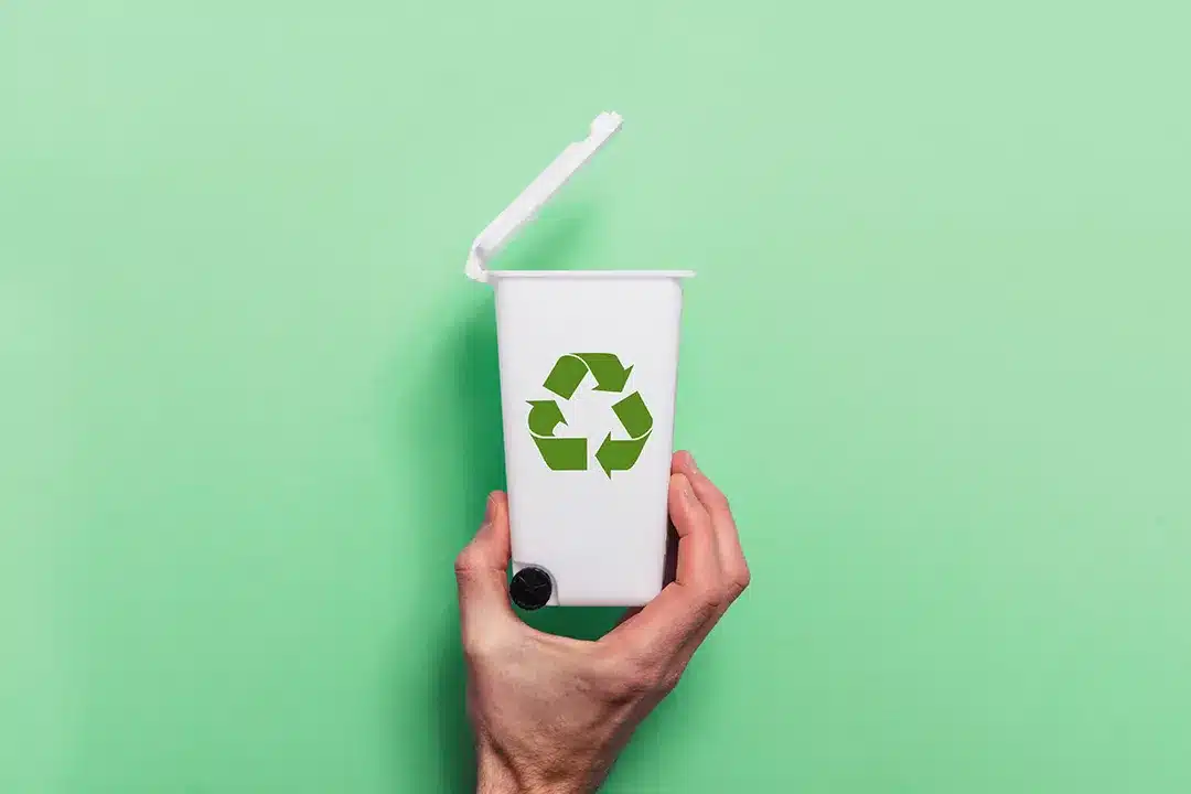 Hand holding a miniature recycling bin