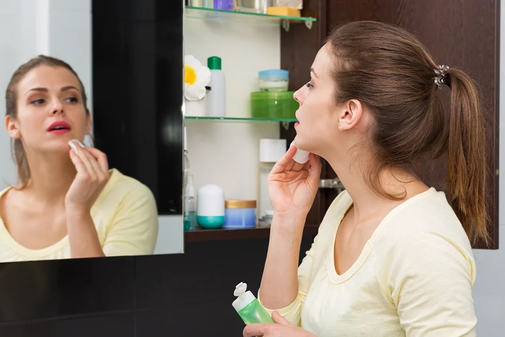 A woman looking at herself in the mirror while touching her chin