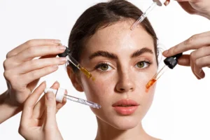 Young woman with multiple pipettes applying serums to her face