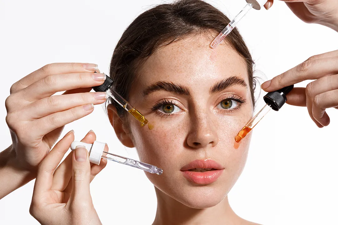 Why Your Skincare Isnt Working Young woman with multiple pipettes applying serums to her face