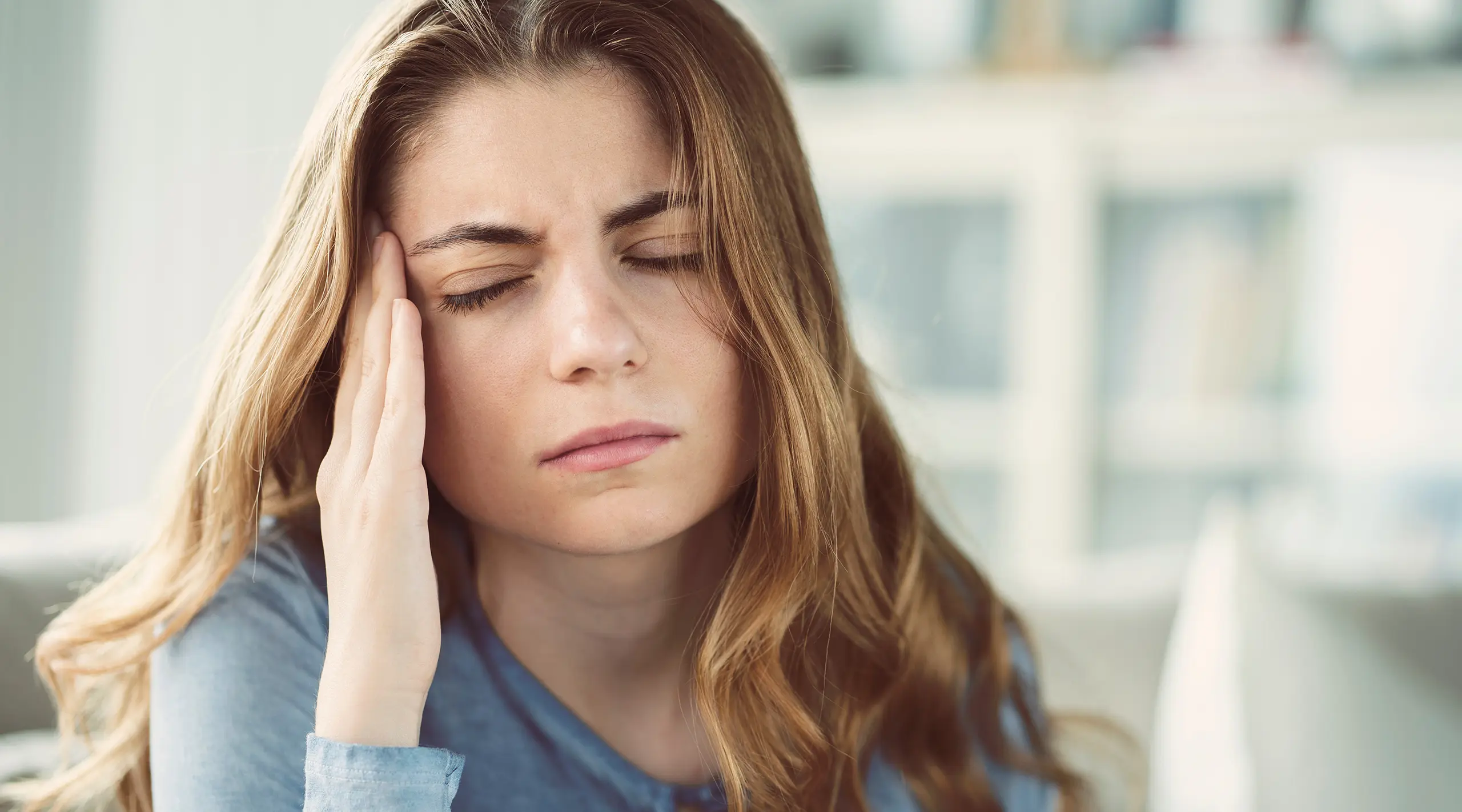 Photo of a woman rubbing her head with a migraine
